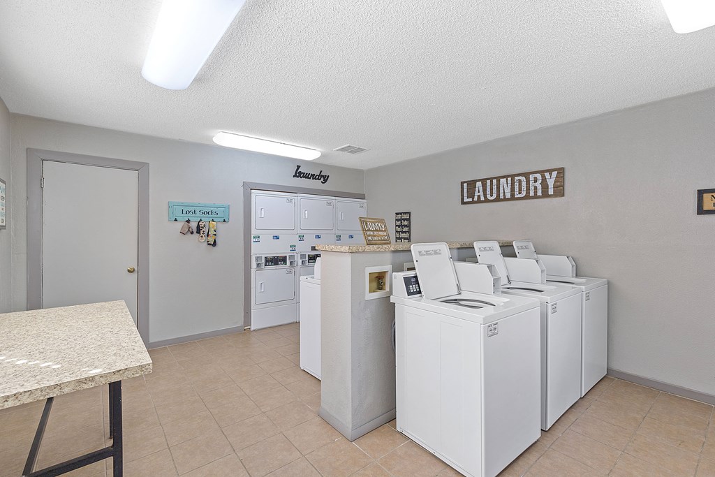 A laundry room with a row of washers and dryers.
