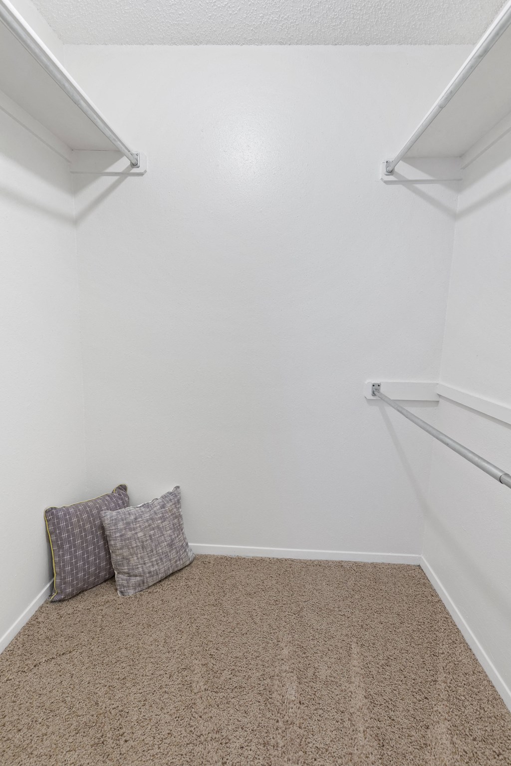 A room with a carpeted floor and two pillows.