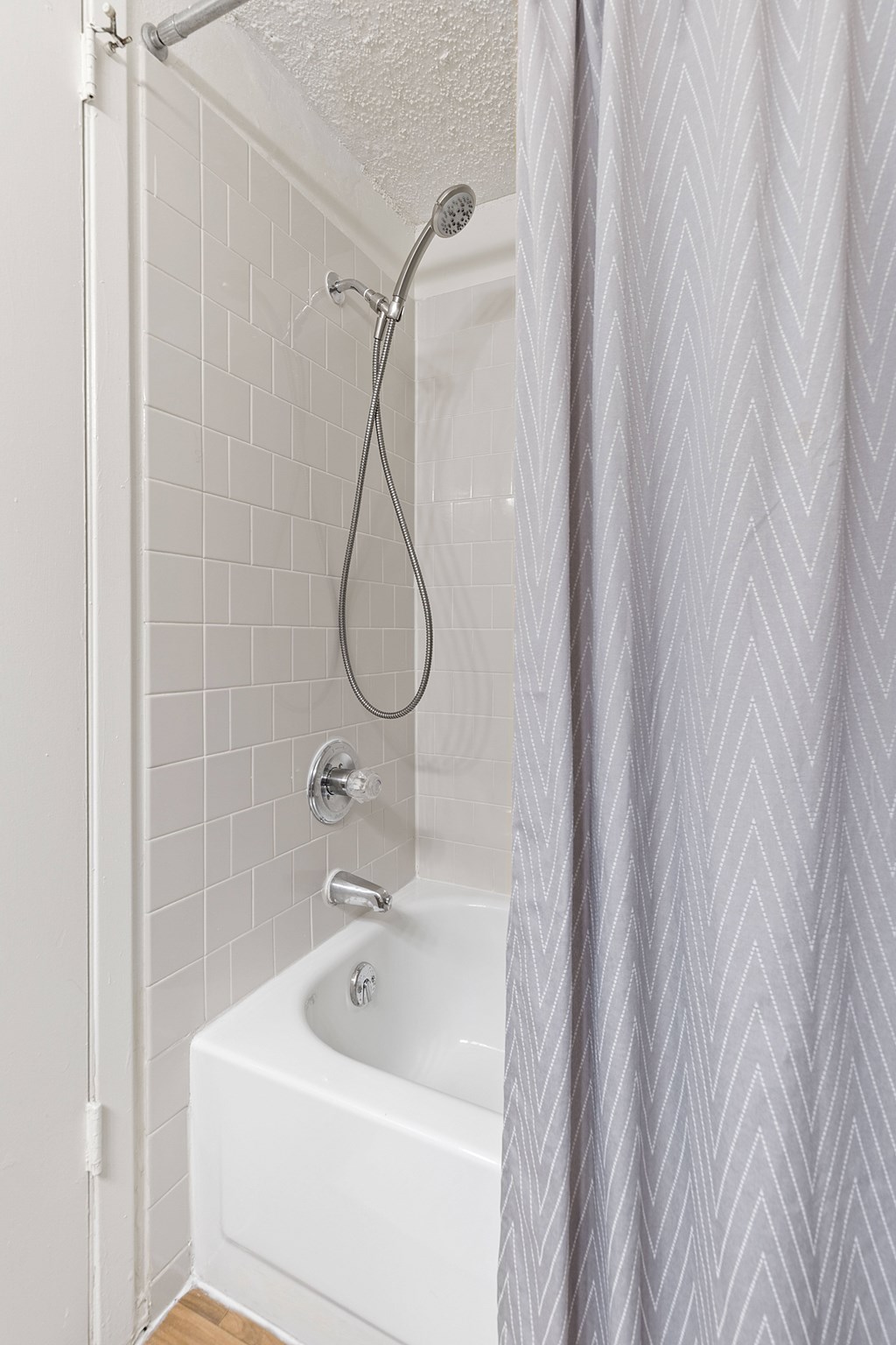 A white bathroom with a white tub and a white shower head.