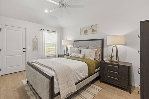 A bedroom with a bed, nightstand, and a ceiling fan.