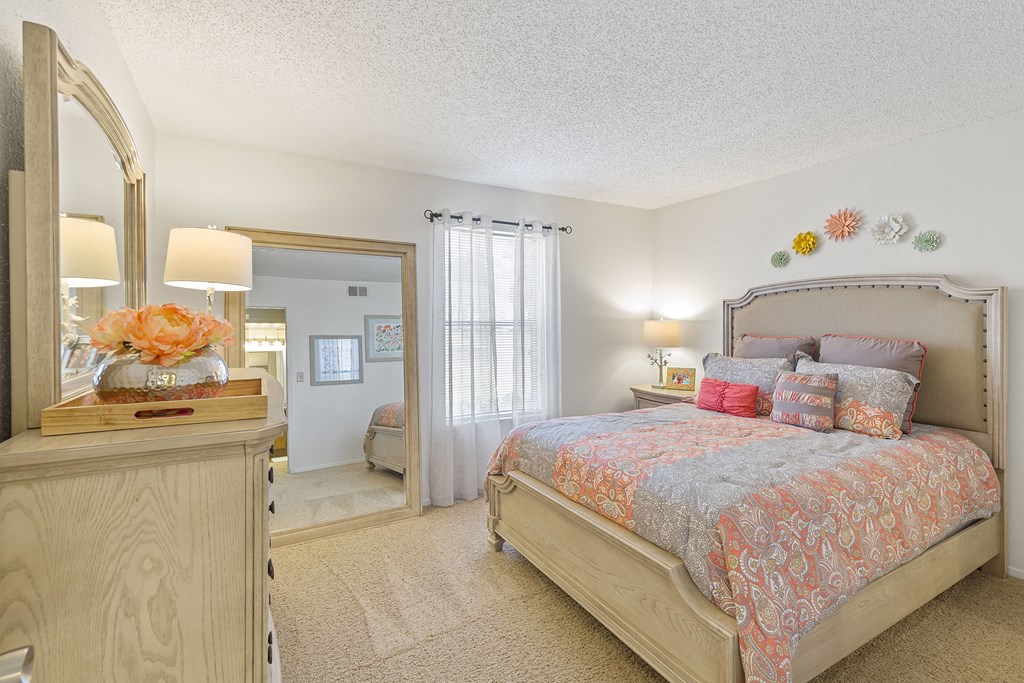 A bedroom with a large bed and a dresser with a mirror.