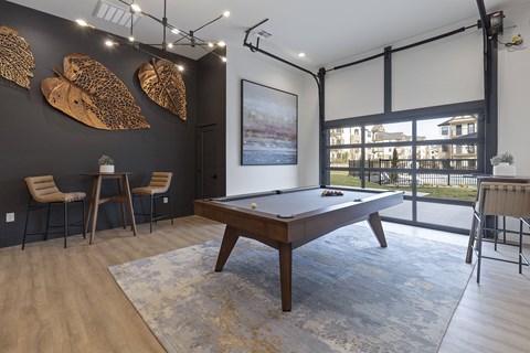A room with a pool table and a painting of a river.