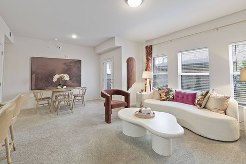 A living room with a white couch, a coffee table, and a painting on the wall.