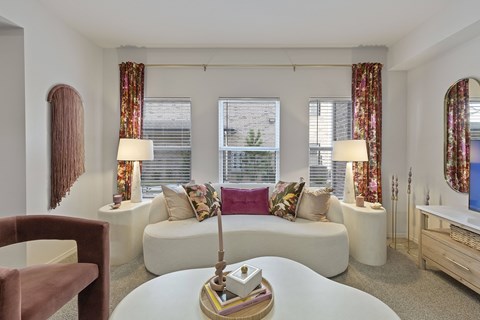 A living room with a white couch, a brown chair, and a white coffee table with a gold and white sculpture on it.