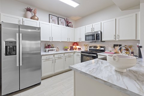 A kitchen with a marble countertop and stainless steel appliances.
