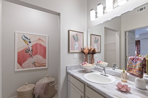 A bathroom with a white sink and a painting of a bird on the wall.