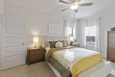 A bedroom with a bed, nightstands, and a ceiling fan.