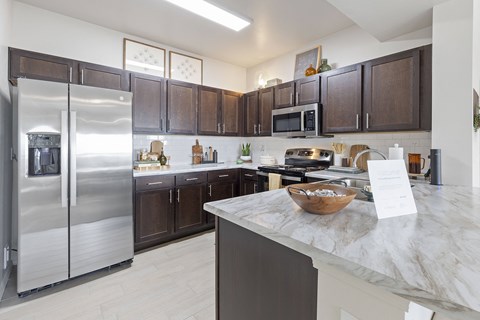A kitchen with a marble counter top and a refrigerator.