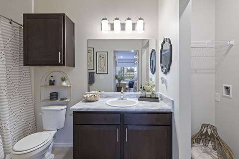 A bathroom with a white toilet and a sink with a brown cabinet.