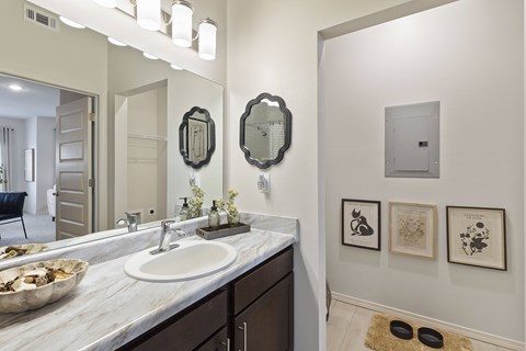 A bathroom with a marble counter top and a large mirror.