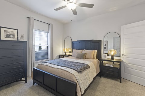 A bedroom with a bed, nightstand, and a ceiling fan.