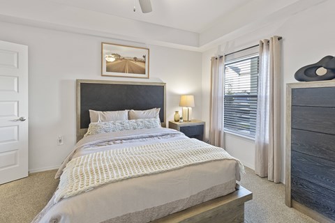 A bedroom with a large bed and a picture on the wall.