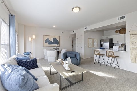 A living room with a white couch, blue chair, and a grey coffee table.
