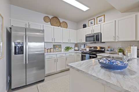 A kitchen with a refrigerator, microwave, and oven.