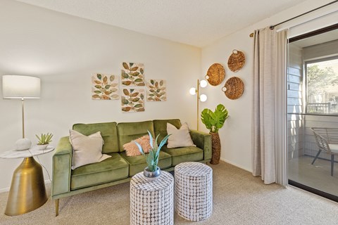 A living room with a green couch, a lamp, and a plant.