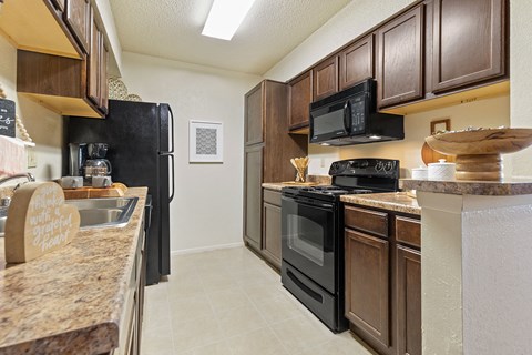 A kitchen with brown cabinets and black appliances.