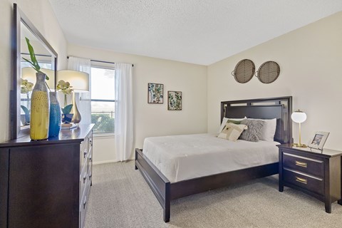 A bedroom with a bed, nightstand, and a dresser with vases on top.