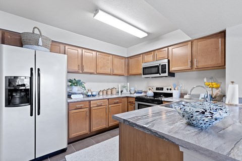A kitchen with a white refrigerator and wooden cabinets.
