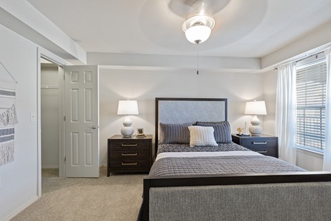 A bedroom with a large bed and two lamps.