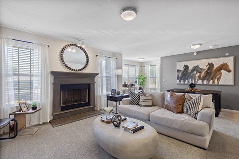 A living room with a fireplace and a painting of horses on the wall.