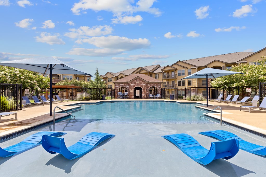 A pool with blue loungers and a building in the background.