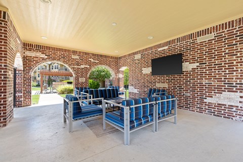 A patio with a couch and a TV mounted on the wall.