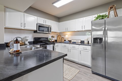 A modern kitchen with a black countertop and stainless steel appliances.