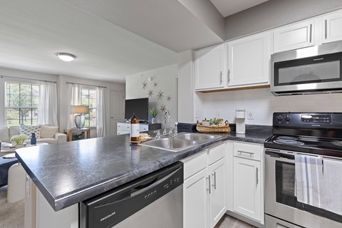 A modern kitchen with white cabinets and a black countertop.