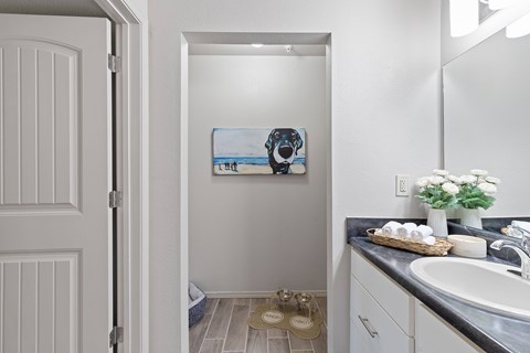 A bathroom with a white door and a painting of a dog on the wall.