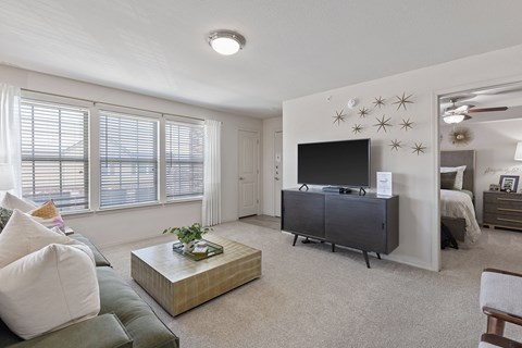A living room with a green couch, a coffee table, and a television.