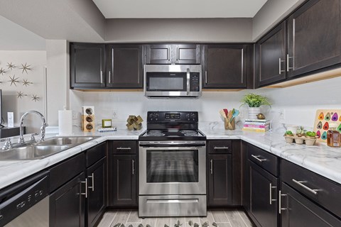 A modern kitchen with dark brown cabinets and stainless steel appliances.