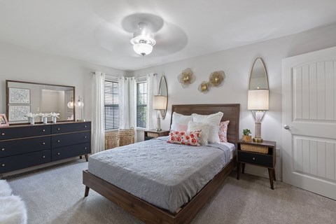 A bedroom with a bed, dresser, and two lamps.