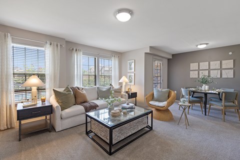 A living room with a white couch, a coffee table, and a dining table with chairs.