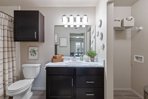 A bathroom with a white toilet, a sink with a mirror above it, and a cabinet above the sink.