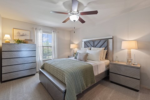 A bedroom with a bed, nightstands, and a ceiling fan.