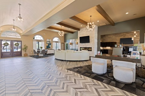 A spacious lobby with a white reception desk and a stone fireplace.