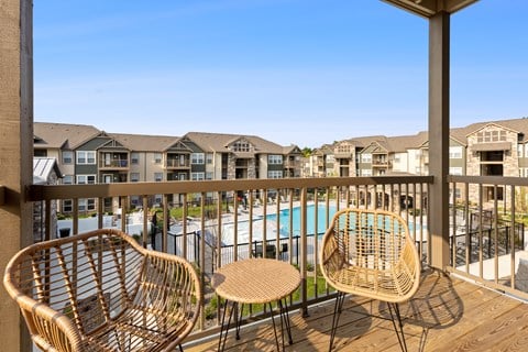 Two wicker chairs on a balcony overlooking a pool.