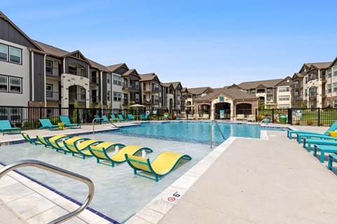 A swimming pool with yellow chairs and a metal ladder.