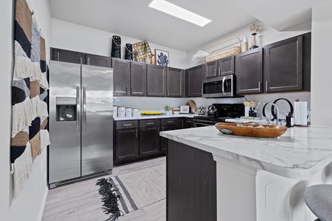 A kitchen with a white counter top and a refrigerator.