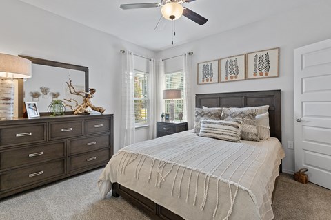 A bedroom with a large bed and a ceiling fan.
