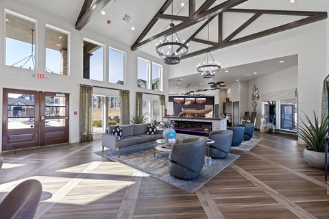 A spacious living room with a grey sofa set and a wooden floor.