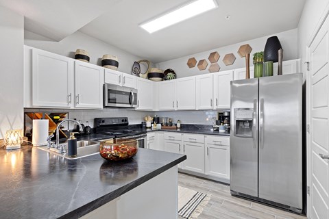 A modern kitchen with a black countertop and stainless steel appliances.