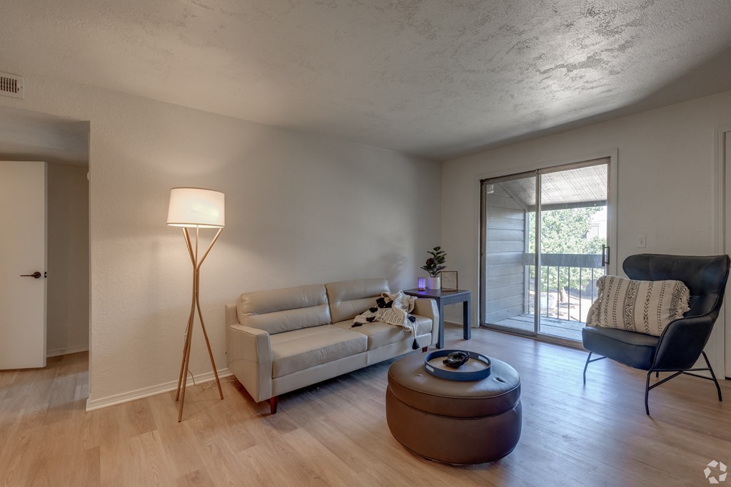 an empty living room with a couch and a chair and a door to a balcony