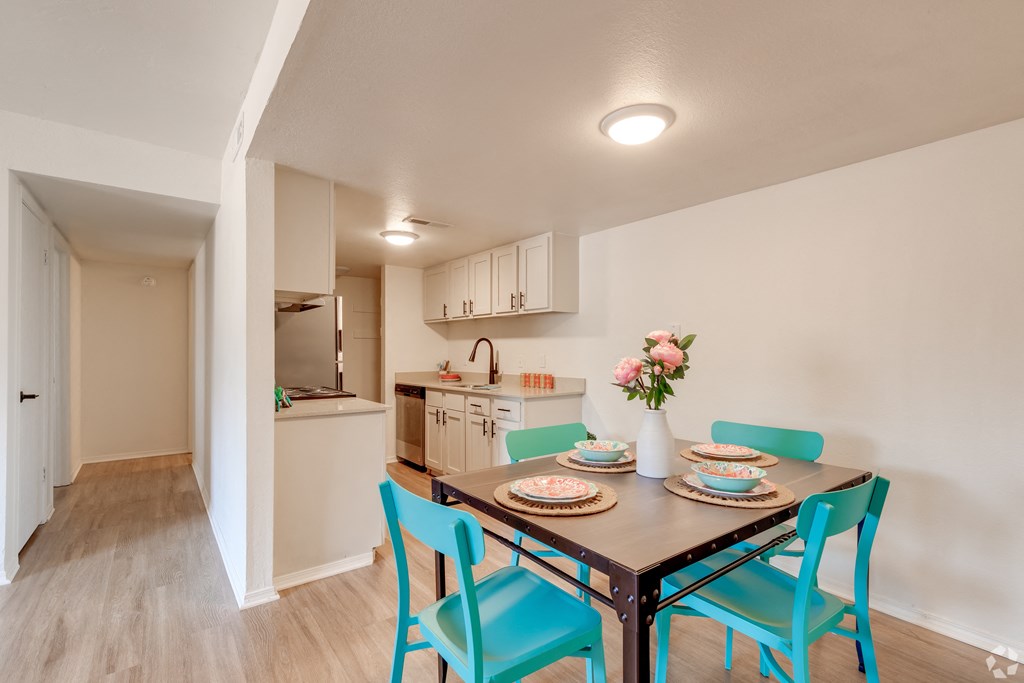 a dining room table with blue chairs and a kitchen in the background