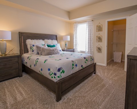 A bedroom with a large bed and two lamps.