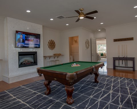 A pool table in a room with a television and fireplace.