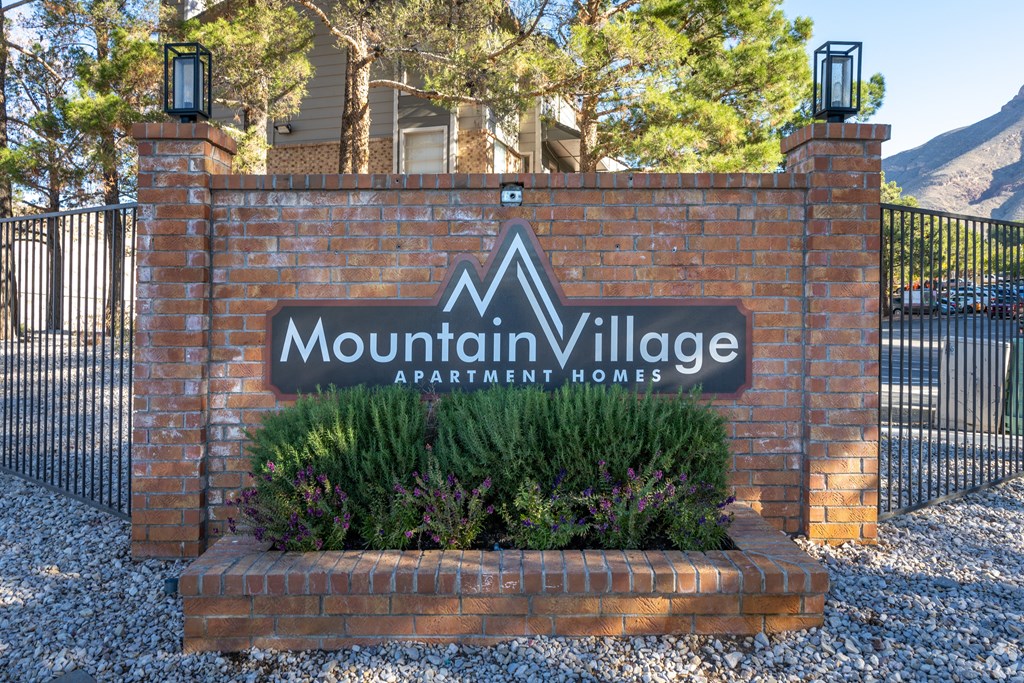 A sign that says Mountain Village in front of a fence.