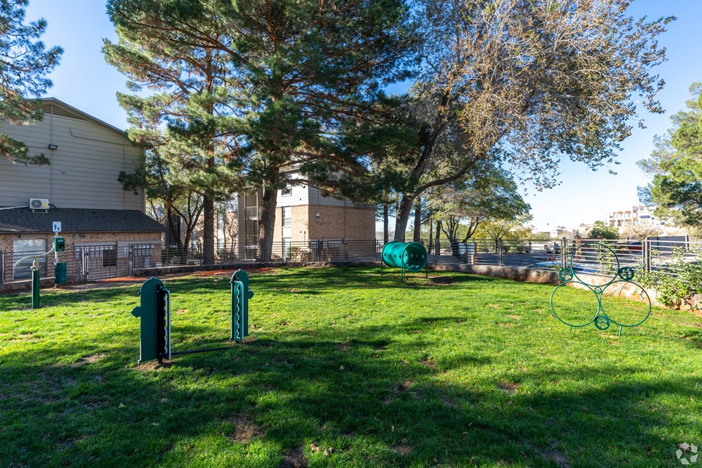 A park with a green lawn, trees, and a playground.