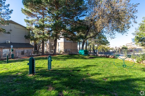 A park with a green lawn, trees, and a playground.