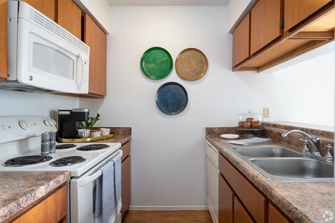 A kitchen with a white stove and a white microwave.